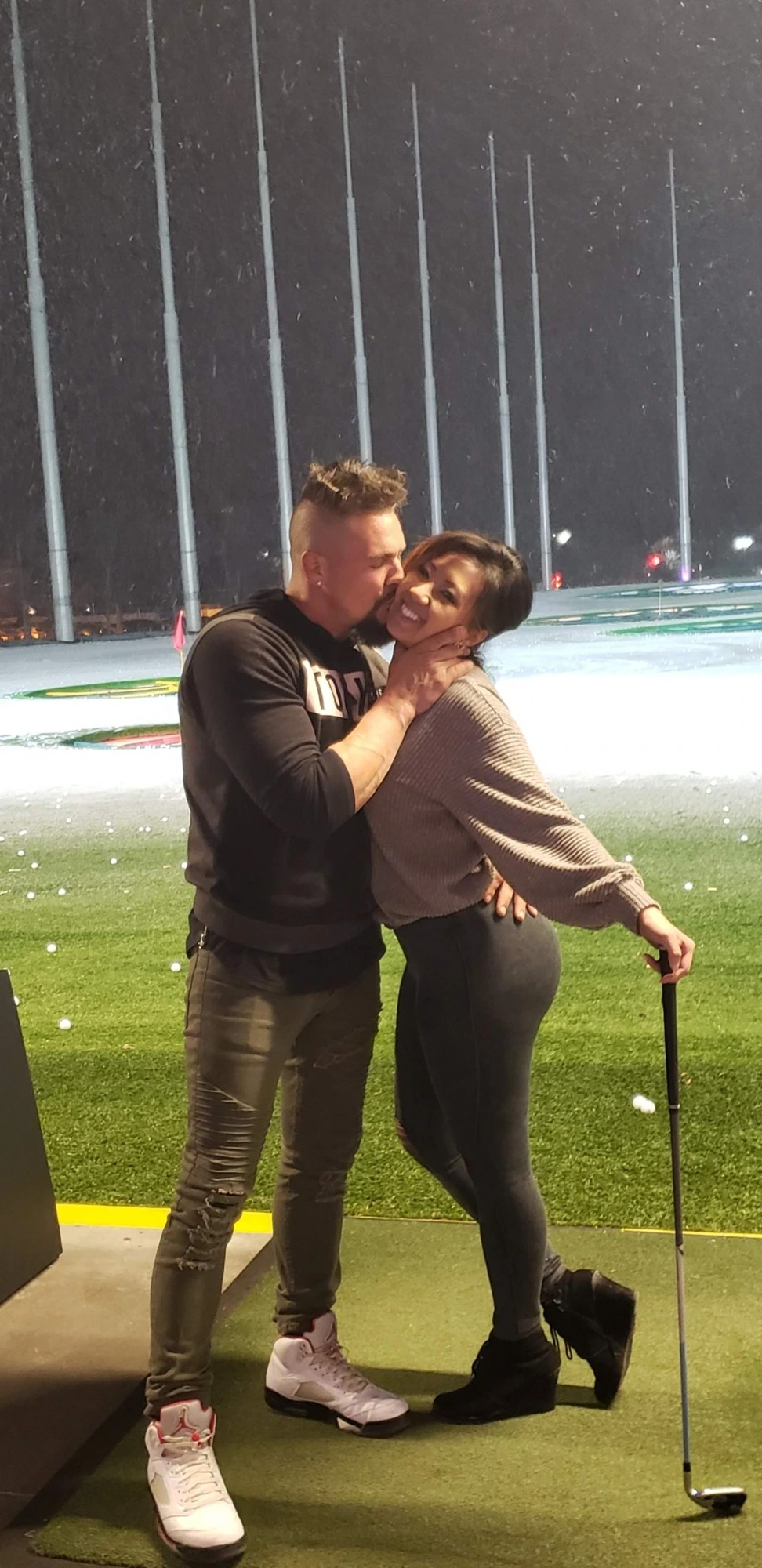 Christopher kissing Mainhia on the cheek at a driving range